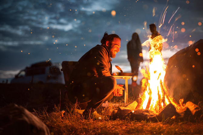 Mann vor loderndem Lagerfeuer