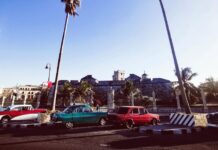 Bunte Autos vor historischer Kulisse in Kuba